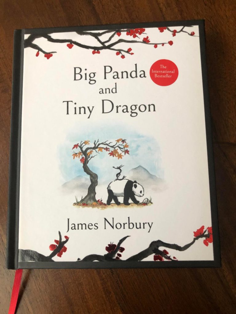 A white cover, with a blossom branch on the top and bottom of the page with red blossoms. There is a panda walking in a tiny image in the canter that has a little dragon on its back and a tree with a few leaves that are red and orange. 