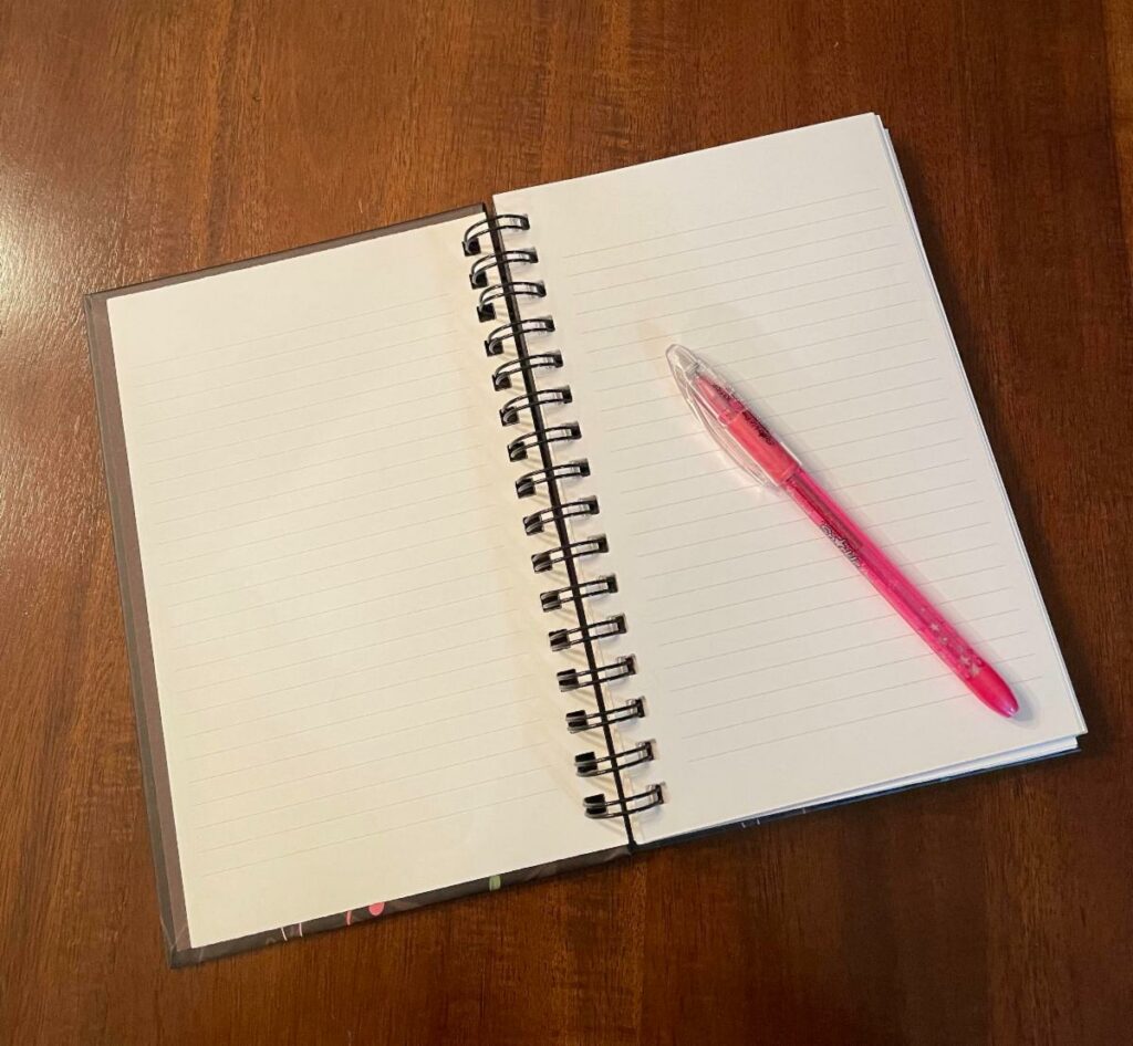 an open notebook with a pencil laying on a blank page