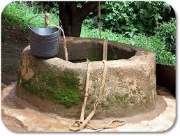 A well with a bucket attached by rope to the well.